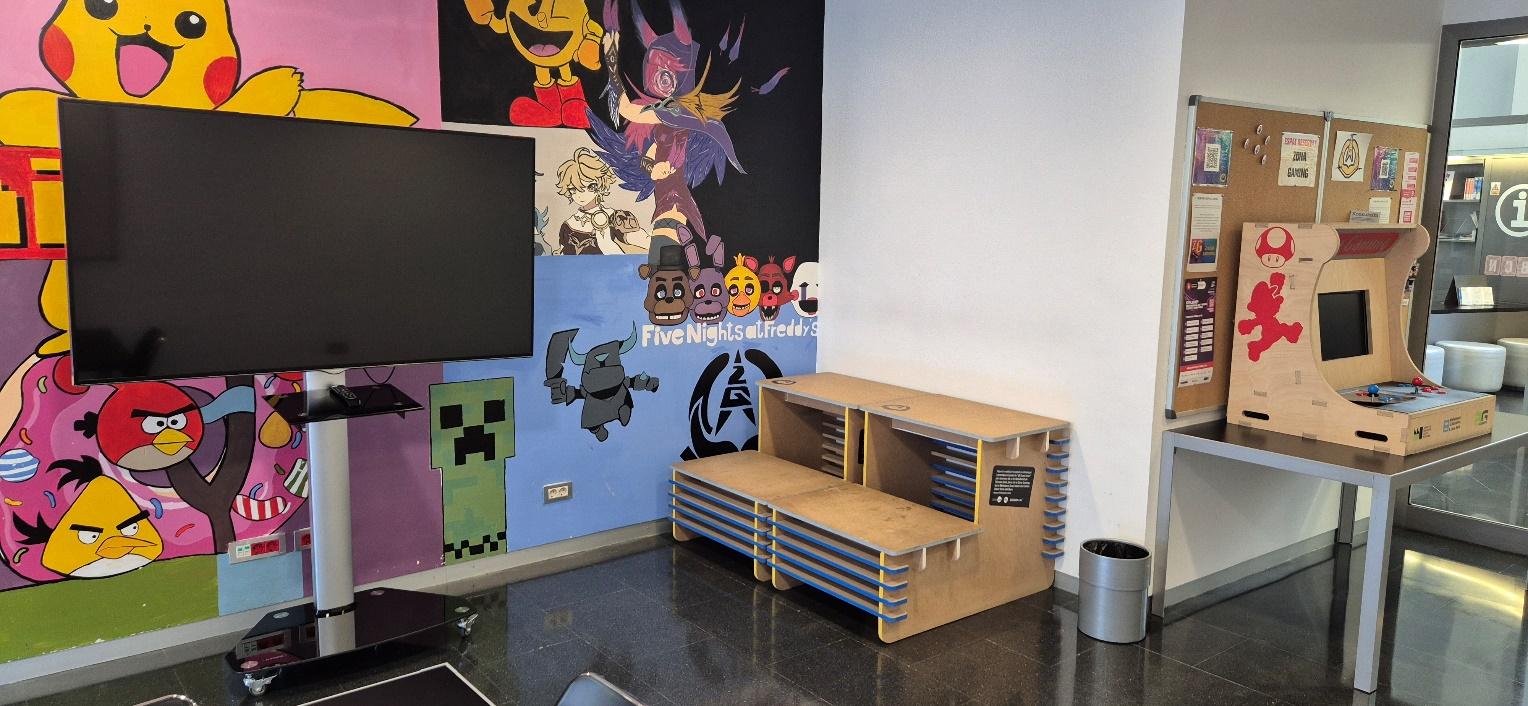 Se ve el mueble-prototipo (en el centro de la imagen) integrado en la Zona Gaming de la biblioteca Zona Nord. A la derecha de la imagen, la máquina de juegos tipo arcade. Fecha de la fotografía: 04/08/2025
